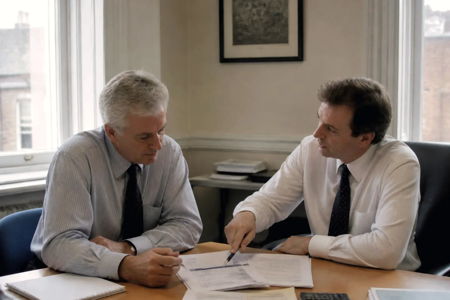 Two advisers reviewing documents together in an established UK professional services office.